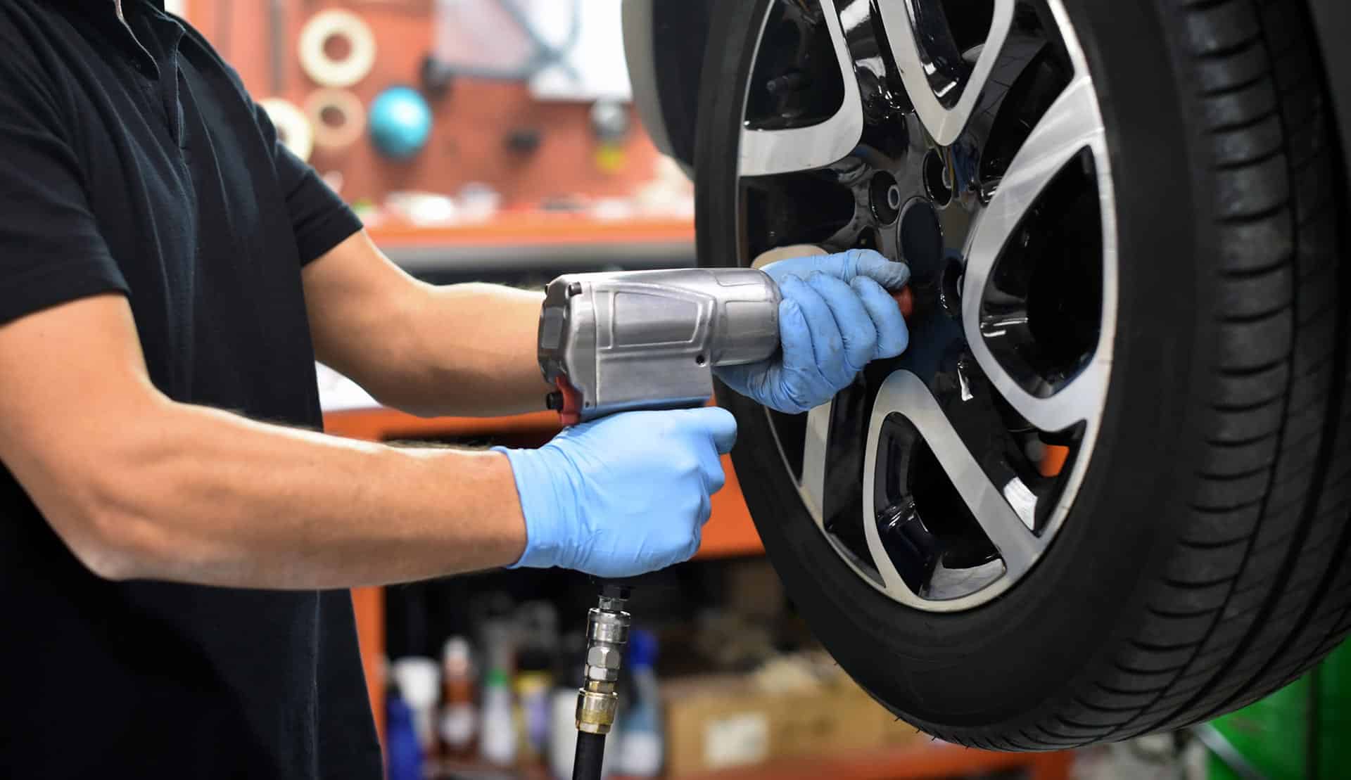 Mechanic using air impact wrench to install tire on vehicle wheel, showcasing tire service expertise at MB Automotive in Bay Shore, NY.