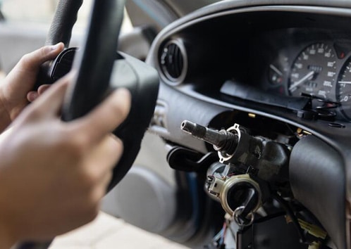 Hands gripping a steering wheel inside a vehicle, focusing on the steering column and dashboard, illustrating steering system mechanics relevant to repair and maintenance services at MB Automotive.