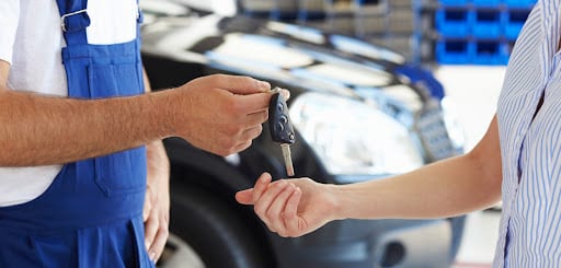 Certified mechanic handing BMW keys to a customer, symbolizing trust and specialized service in vehicle maintenance.