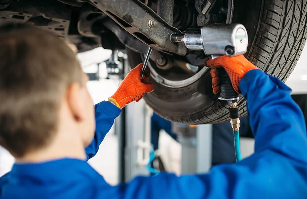 technician with a wrench repair car suspension EB35GKC