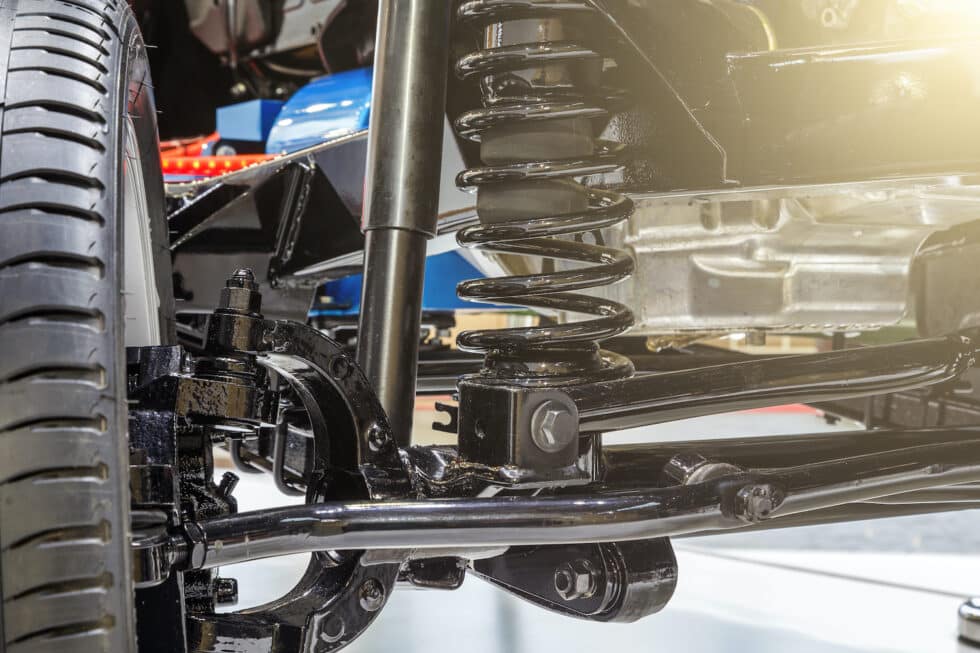 Close-up of a vehicle's front suspension system featuring a coil spring, shock absorber, and control arm, highlighting the components critical for ride comfort and vehicle handling.