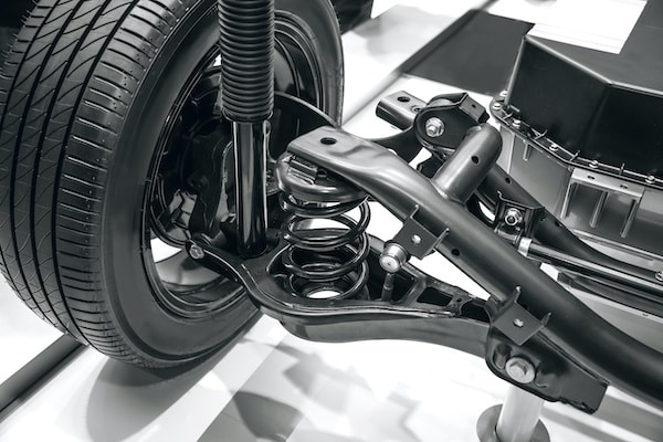 Close-up of a car's suspension system, featuring a wheel, tire, and components like springs and shock absorbers, relevant to CV joint inspection and axle repair services.