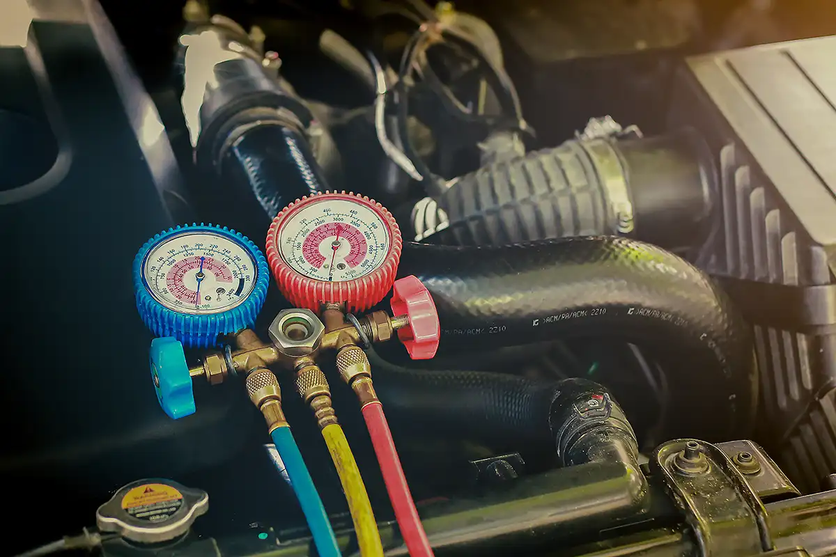 Engine cooling system pressure gauges with blue and red dials, measuring coolant pressure in a vehicle's engine compartment, emphasizing MB Automotive's cooling system repair services.