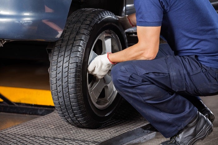 Mechanic performing tire repair service on a vehicle at MB Automotive, showcasing expertise in tire maintenance and safety.
