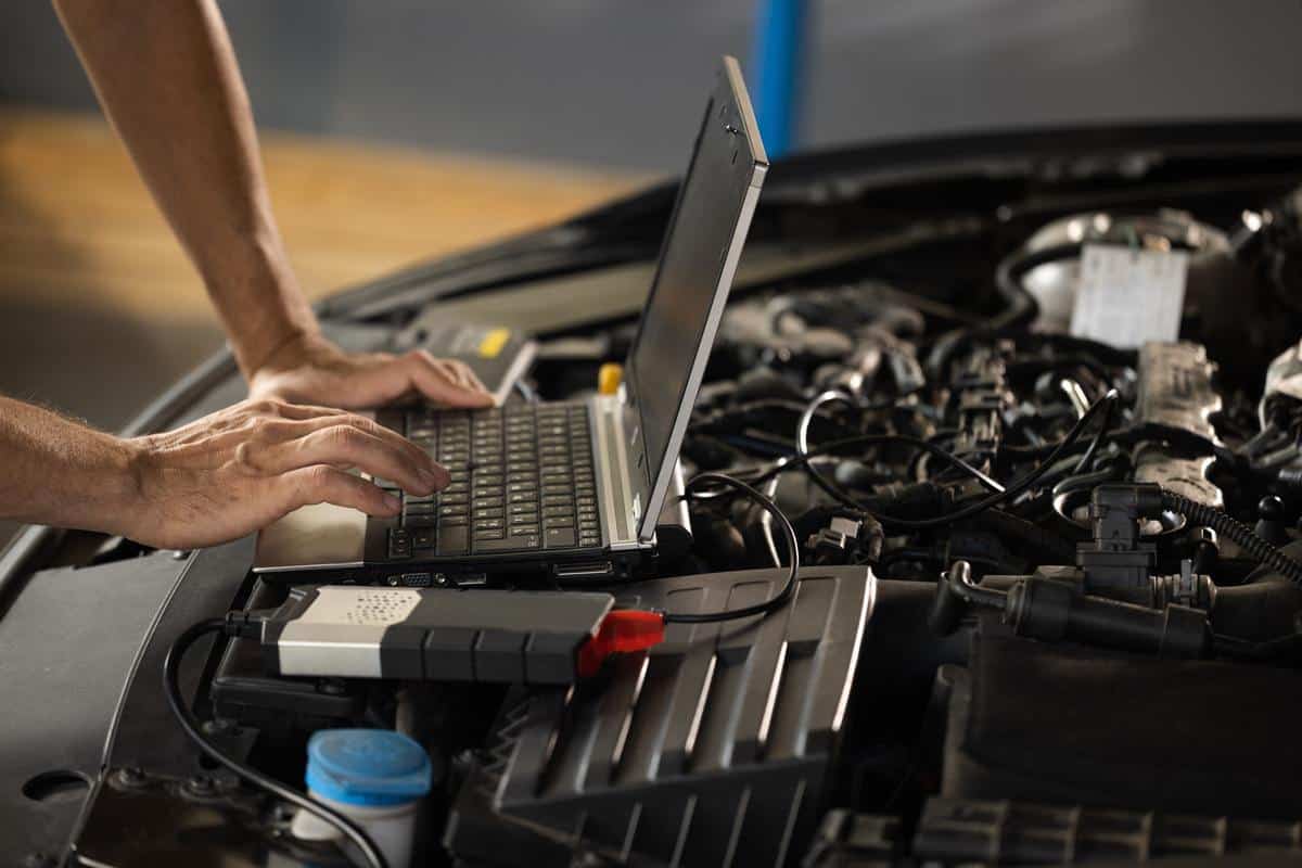 Mechanic using a laptop for auto diagnostics on a BMW engine, showcasing advanced vehicle maintenance technology.