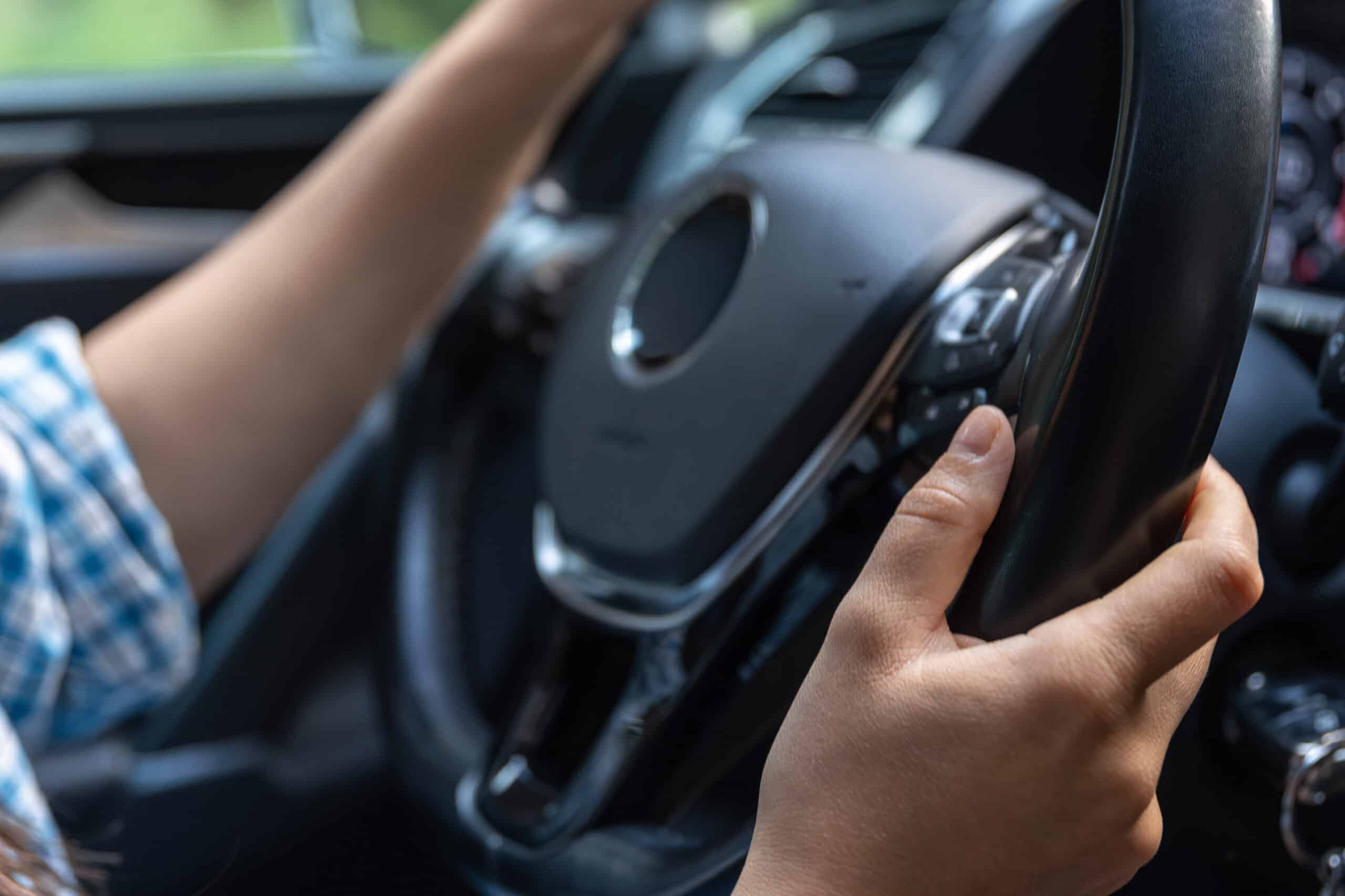 female hands car steering wheel while driving focus details safety scaled 1
