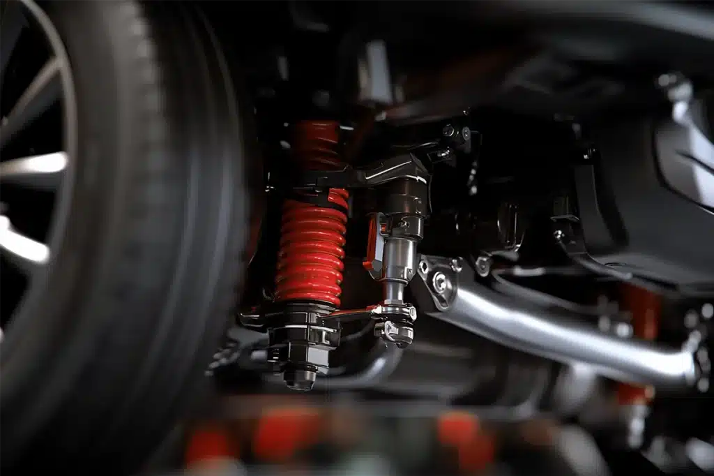 Close-up of automotive suspension system with red coil spring and wheel, highlighting key components relevant to same-day brake services at MB Automotive in Suffolk County.