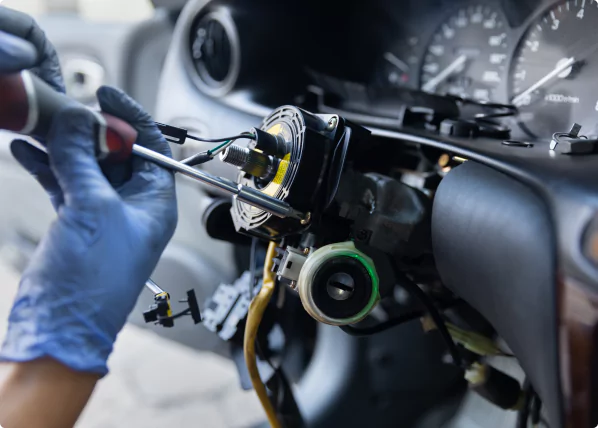 Mechanic repairing vehicle steering system components with tools, highlighting power steering assembly and dashboard instruments.