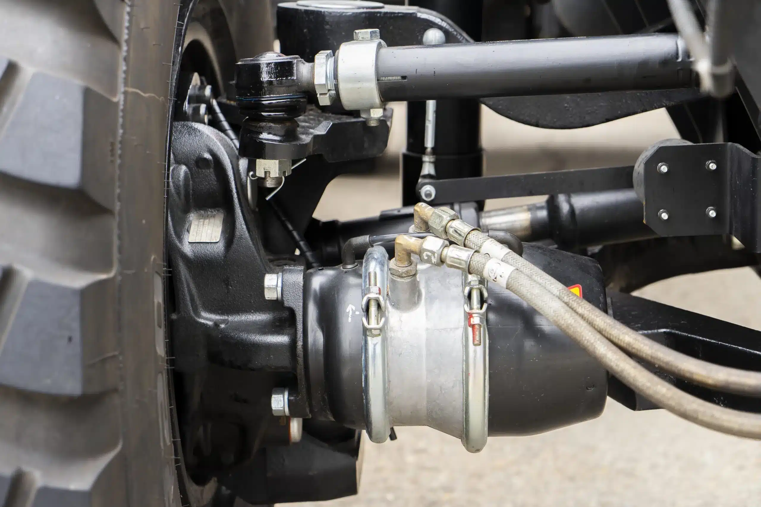 Close-up of a vehicle's steering suspension system, highlighting hydraulic components and hoses, relevant to steering system repair and maintenance services offered by MB Automotive in Seattle.