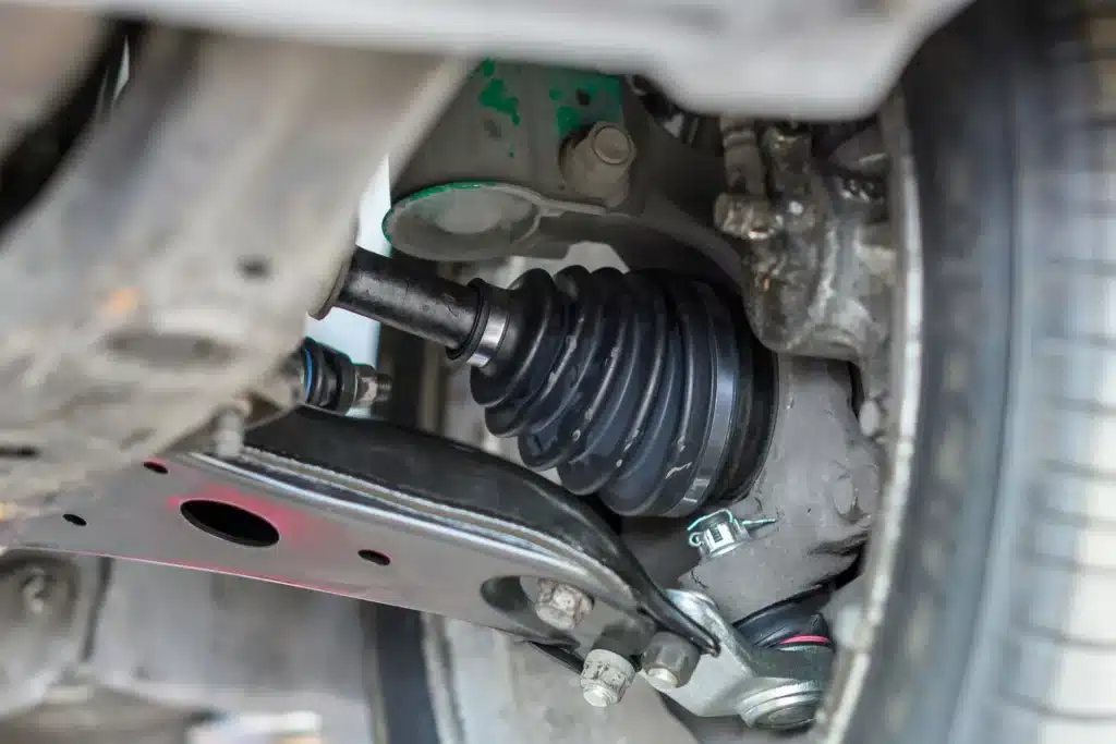 Close-up of a CV joint drive axle on a front-wheel-drive Mercedes-Benz vehicle, highlighting the boot and surrounding suspension components, relevant for discussions on automotive maintenance and repair.