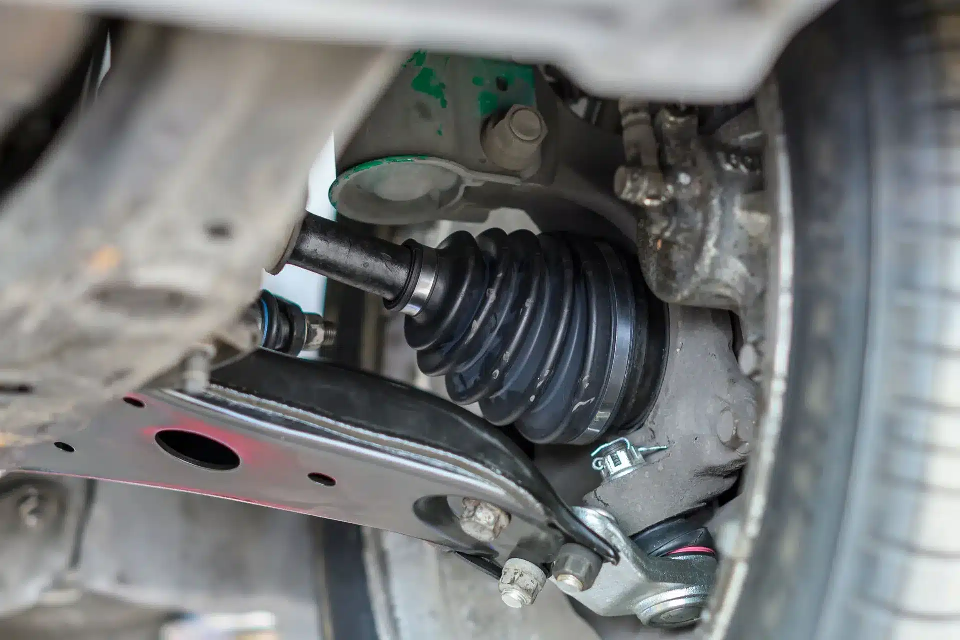 Close-up of a CV joint and axle assembly on a front-wheel-drive car, highlighting the protective CV boot and surrounding drivetrain components.