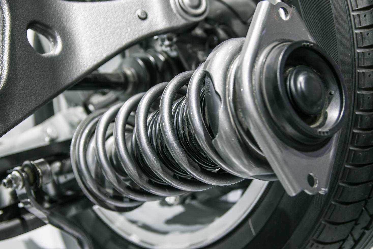 Close-up of a vehicle suspension coil spring and shock absorber assembly, highlighting essential components for steering and suspension services at MB Automotive.